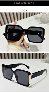 Detail of square black sunglasses with integrated nose pads and gold metal hinge accents