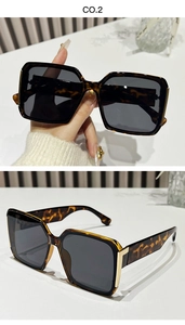 Detail of square oversized tortoiseshell sunglasses with golden metal hinges and dark lenses
