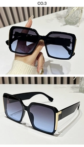 Detail of square sunglasses with black frame, gold hinges, and blue-gray gradient lenses