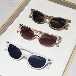 Chic cat-eye sunglasses set with metallic rivet accents on minimalist display tray