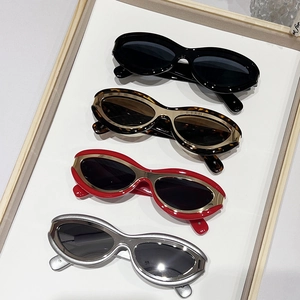Retro oval sunglasses in black, tortoiseshell, red, and silver frames on a tray