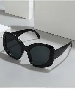 Close-up of black oversized butterfly sunglasses on a geometric white studio display