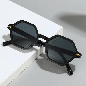 Retro small hexagonal frame sunglasses in black with gold metal accents on white blocks