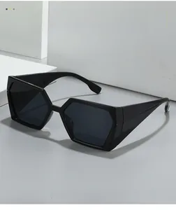 Gros plan de lunettes de soleil carrées géométriques noires sur une surface grise épurée