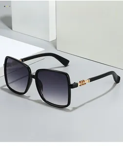 Detail of oversized black square sunglasses with gradient lenses and gold temple accents