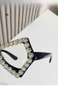 Detail showing oversized black frame with sparkling rhinestones and butterfly shape
