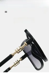 Detailed close-up of golden metal hinge on black oversized square sunglasses frame