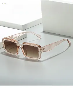 Detailed close-up of champagne rectangle sunglasses with gradient brown lenses