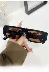 Detail of black rectangular sunglasses featuring a golden leopard ornament on the lens