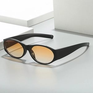 Minimalist oval sunglasses with black frame and orange gradient lenses on geometric blocks