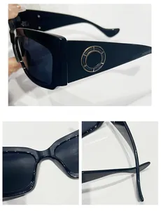 Détail de lunettes de soleil noires à monture rectangulaire épaisse et cercles dorés latéraux