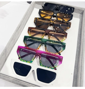 Detailed view of various colorful square frame sunglasses on a gray display tray