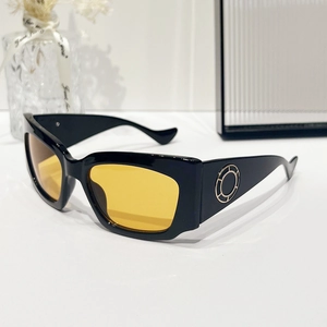 Lunettes de soleil à monture noire, verres jaunes et anneaux dorés aux branches