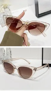 Detail showing cat-eye sunglasses with champagne pink frames and brown gradient lenses