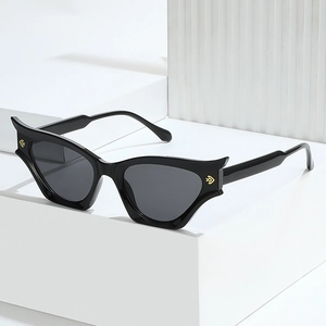 Modern cat-eye sunglasses with black frames and gold accents against a geometric backdrop