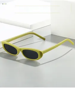 Detail view of oval cat-eye sunglasses with light green frame on white geometric blocks