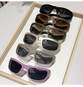 Flat lay of six colorful Y2K futuristic sports sunglasses in a wooden display tray