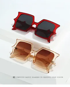 Detail of trendy star-shaped rectangular sunglasses in deep red and amber finish