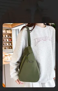 Olive green nylon teardrop sling bag for men and women worn in a casual bookstore setting