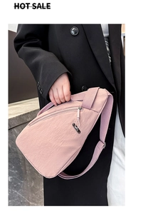 Pink nylon crossbody bag detail with adjustable strap and zip pockets on black blazer