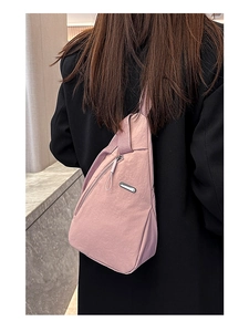 Rear view of model wearing a pink nylon crossbody chest bag over a black blazer