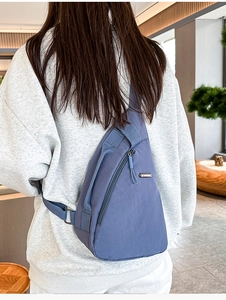 Close-up of fog blue nylon chest bag featuring smooth zippers and premium metal logo detail