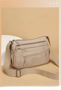 Close-up of beige multi-compartment nylon shoulder bag with adjustable wide strap