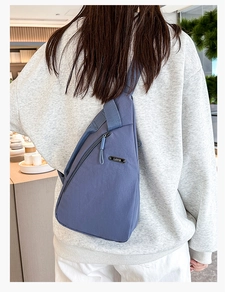 Detail of dark blue nylon chest bag featuring LSNR metal logo and adjustable strap