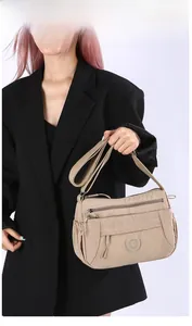 Detail of khaki nylon crossbody bag with multiple zippers and wide adjustable strap