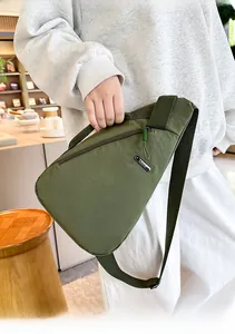 Detail of dark green nylon chest bag featuring a front zipper pocket and adjustable strap