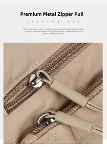 Close-up of polished silver metal dual zippers and durable nylon fabric texture on khaki bag