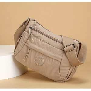 Detail of beige nylon crossbody bag showing dual front zippers and adjustable strap