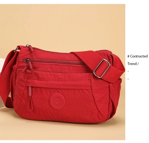 Detail of red water-resistant nylon shoulder bag featuring multiple zip compartments