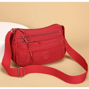 Detail view of red multi-pocket nylon shoulder bag with adjustable strap and logo