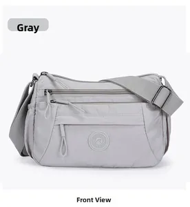 Front detail of grey nylon crossbody bag with multiple zipper pockets and adjustable strap