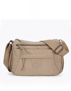 Front view detail of khaki nylon crossbody bag showing multi-zip pockets and adjustable strap