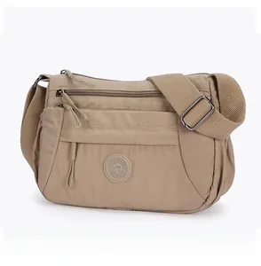Micro side view of beige nylon crossbody bag with multi-zipper compartments and wide strap