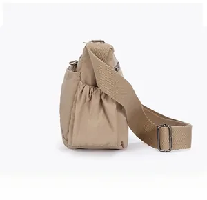 Side view of beige nylon crossbody bag with elastic pocket and adjustable shoulder strap