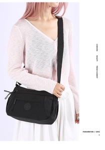 Detail of black nylon crossbody bag featuring multiple zipper pockets and wide fabric strap