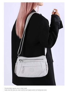 Light gray nylon crossbody bag with multiple zippers shown on model for daily commuting
