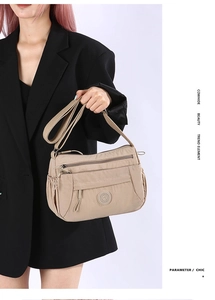 Close-up of multi-zipper compartments and nylon fabric on beige crossbody bag
