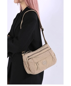 Khaki multi-pocket nylon crossbody bag worn by a model in a black suit for casual use