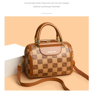 Detail of brown checkered leather Boston bag with gold hardware on display stand