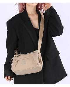 Detail of multi-compartment nylon crossbody bag with zipper pockets and adjustable strap