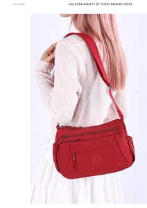 Detail view of red multi-pocket nylon shoulder bag with adjustable strap on model