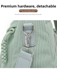 Detail of light green corduroy texture with high-gloss silver metal hooks and detachable strap
