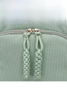 Detail of smooth sage green corduroy fabric and dual zippers with woven rope pulls