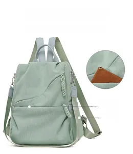 Detail view of mint green corduroy backpack with multi-pocket design and strap options