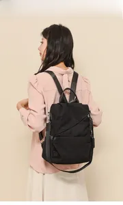 Back view of a black corduroy backpack with leather straps on a model in casual style