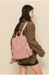 Side view of a pink corduroy backpack worn by a model against a beige background